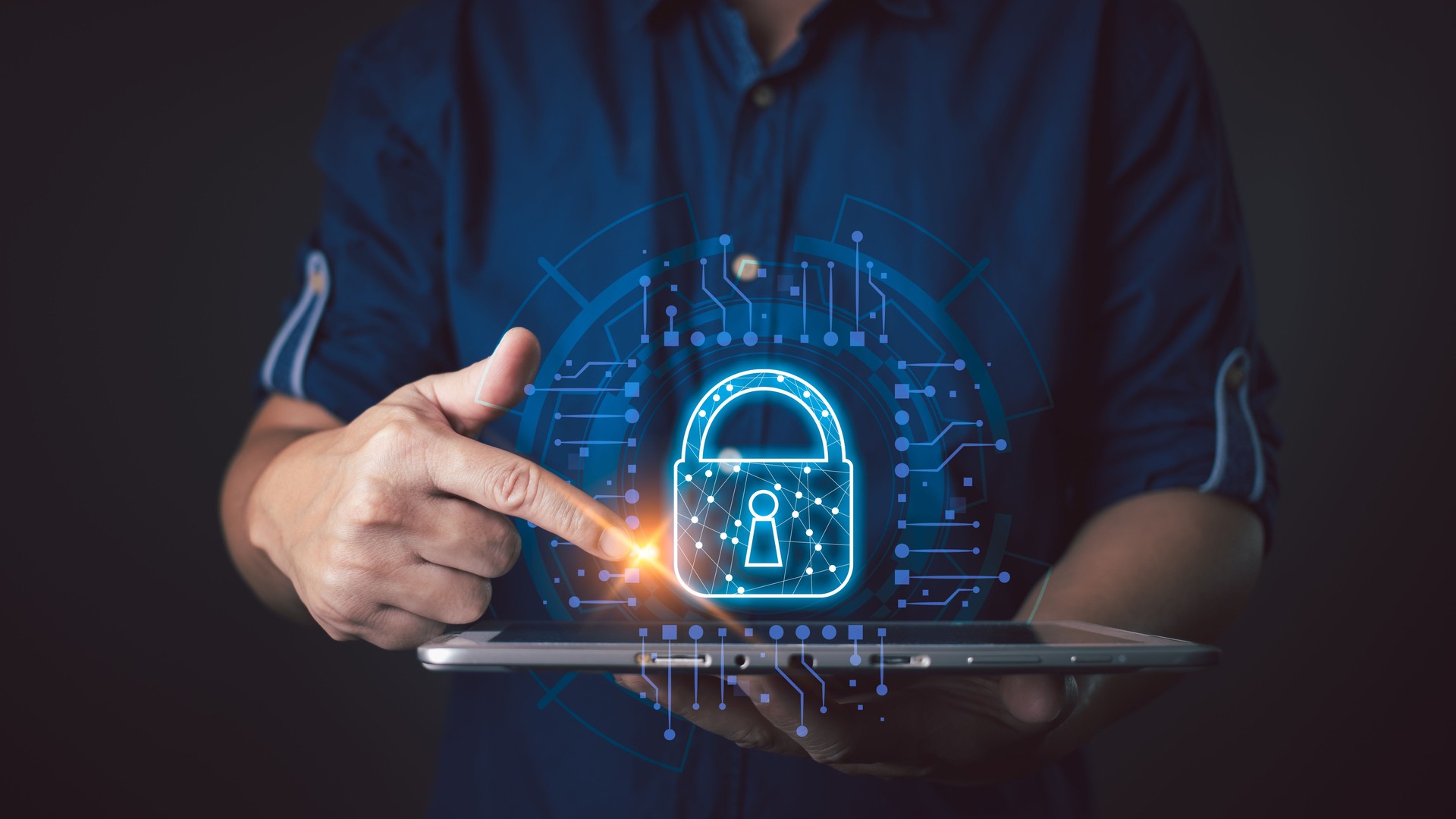 Une personne interagit avec une icône de cadenas lumineuse sur une tablette, symbolisant la protection sécurisée des cyberdonnées, mettant en valeur la technologie, l’innovation et la protection des informations sensibles à l’ère numérique.